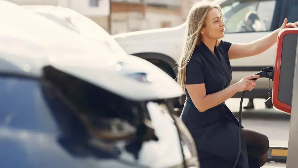 Woman using charging station to boost electromobile, highlighting Charging Stations Business Boost.