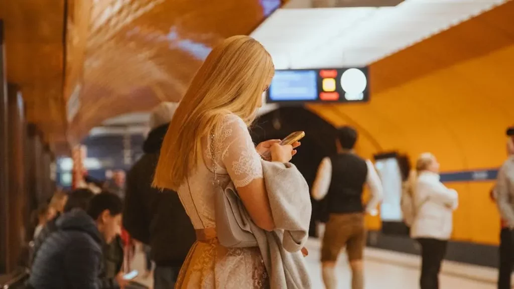 Woman using smartphone near Phone Charging Station Rentals in Munich subway.