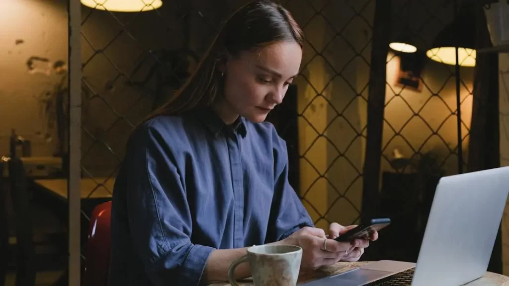 Woman texting on smartphone at cafe with phone charging station