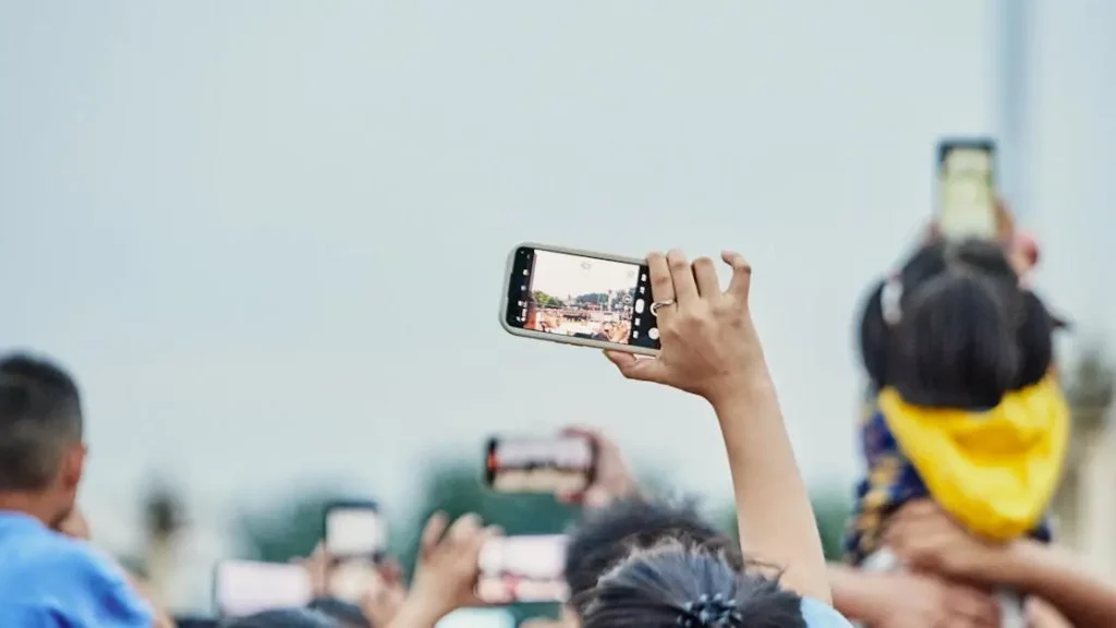 Smartphone recording in a crowd, showcasing the benefits of mobile charge stations at events.