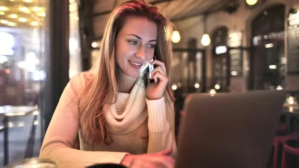 Woman on phone at cozy cafe, illustrating Phone Power Stations as Customer Magnets.