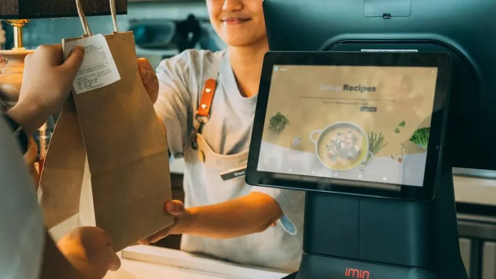 Smiling cashier enhancing customer satisfaction for higher retention rates at a modern point of sale.