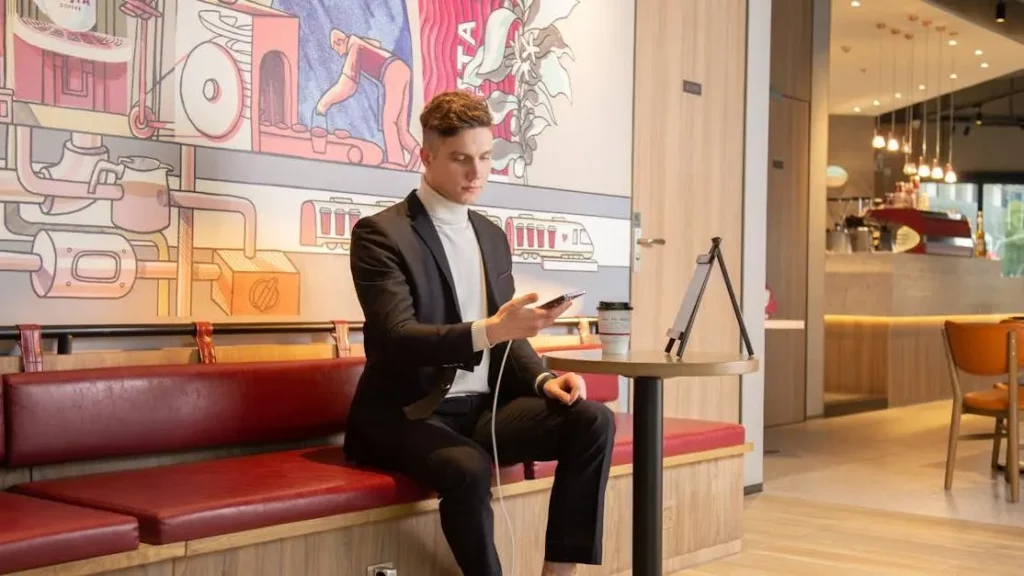 Choosing the Right Charging Station: Businessman charging phone in stylish cafe.