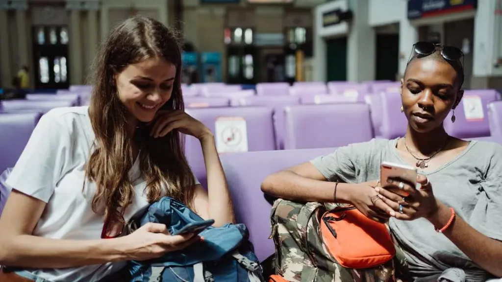 Women using smartphones in a venue, highlighting benefits of installing charging kiosks.