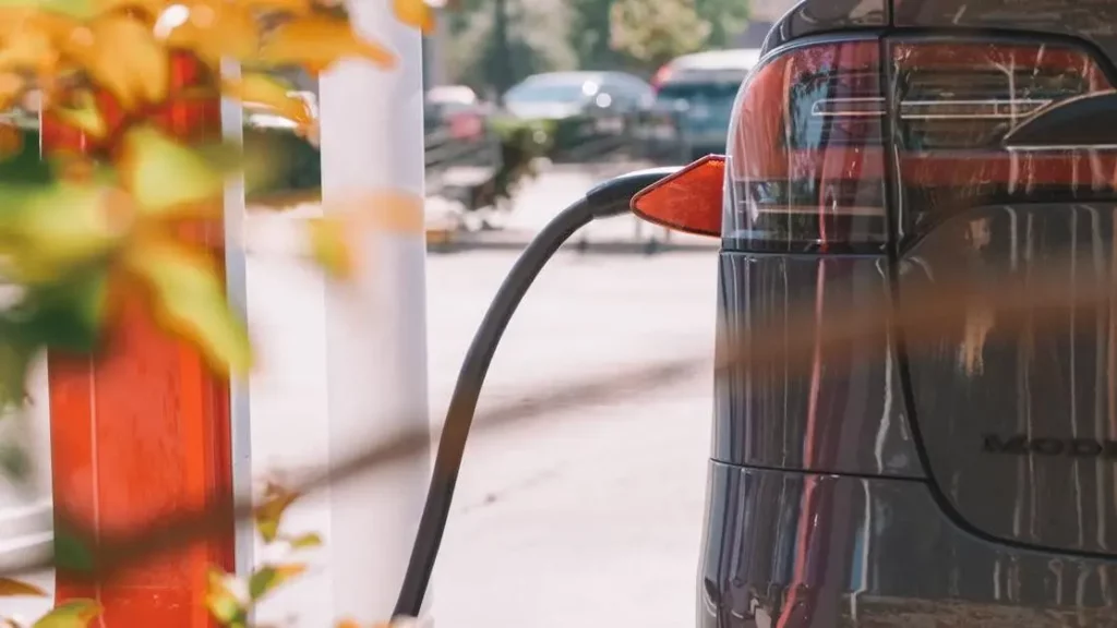 Electric car charging at a station, highlighting "5 Features to Look for in a Phone Charging Rental Station".