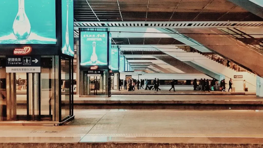 Modern train station bustling with people and billboards, highlighting Charging Station Rentals.