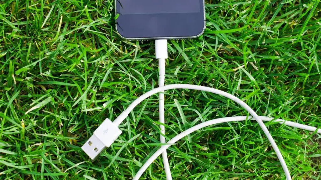 Smartphone charging on grass showcasing The Sustainability Benefits of Portable Charging Rentals.