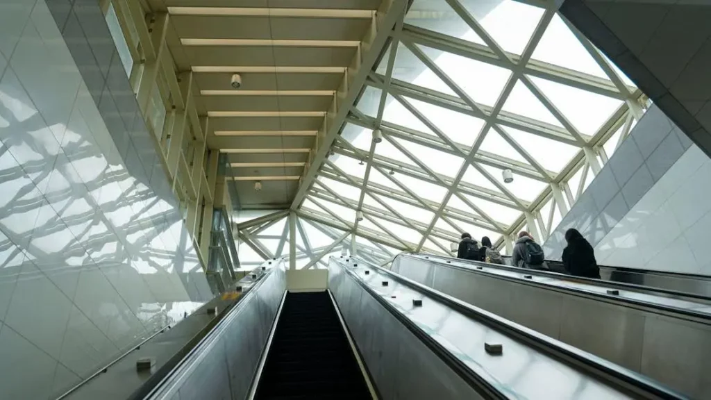 Modern terminal with escalators and travelers, highlighting the concept of Renting Phone Charging Kiosks.