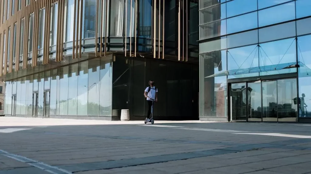 Urban mobility with electric scooter by office building, highlighting Charging Rentals Over Fixed Outlets.