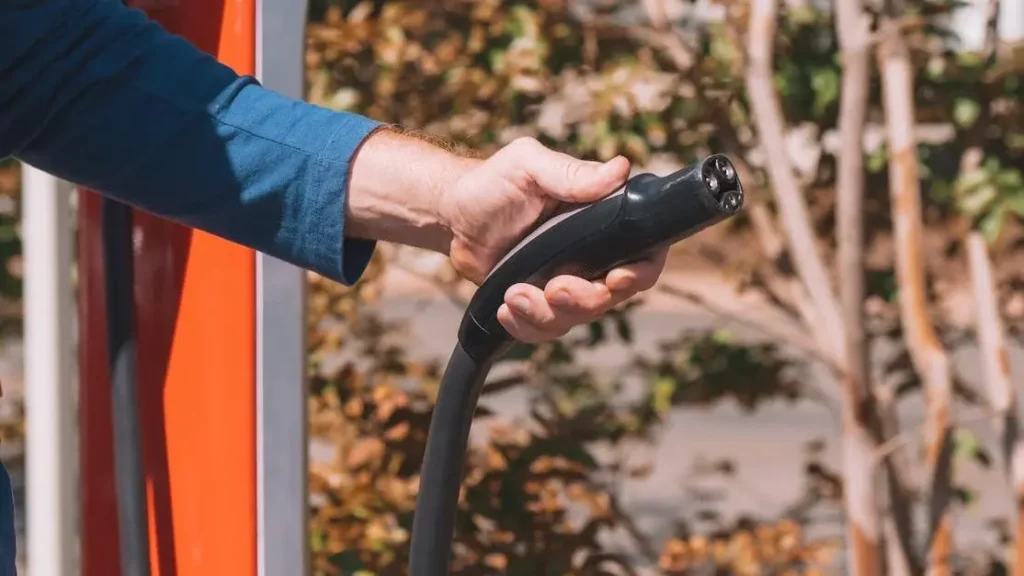 Electric vehicle charger held outdoors at station among autumn trees for Zappy Chargers Every Venue Type.